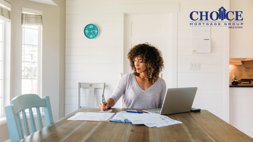 Dark curly haired women at table working on finances with laptop, white wall background with green clock on wall